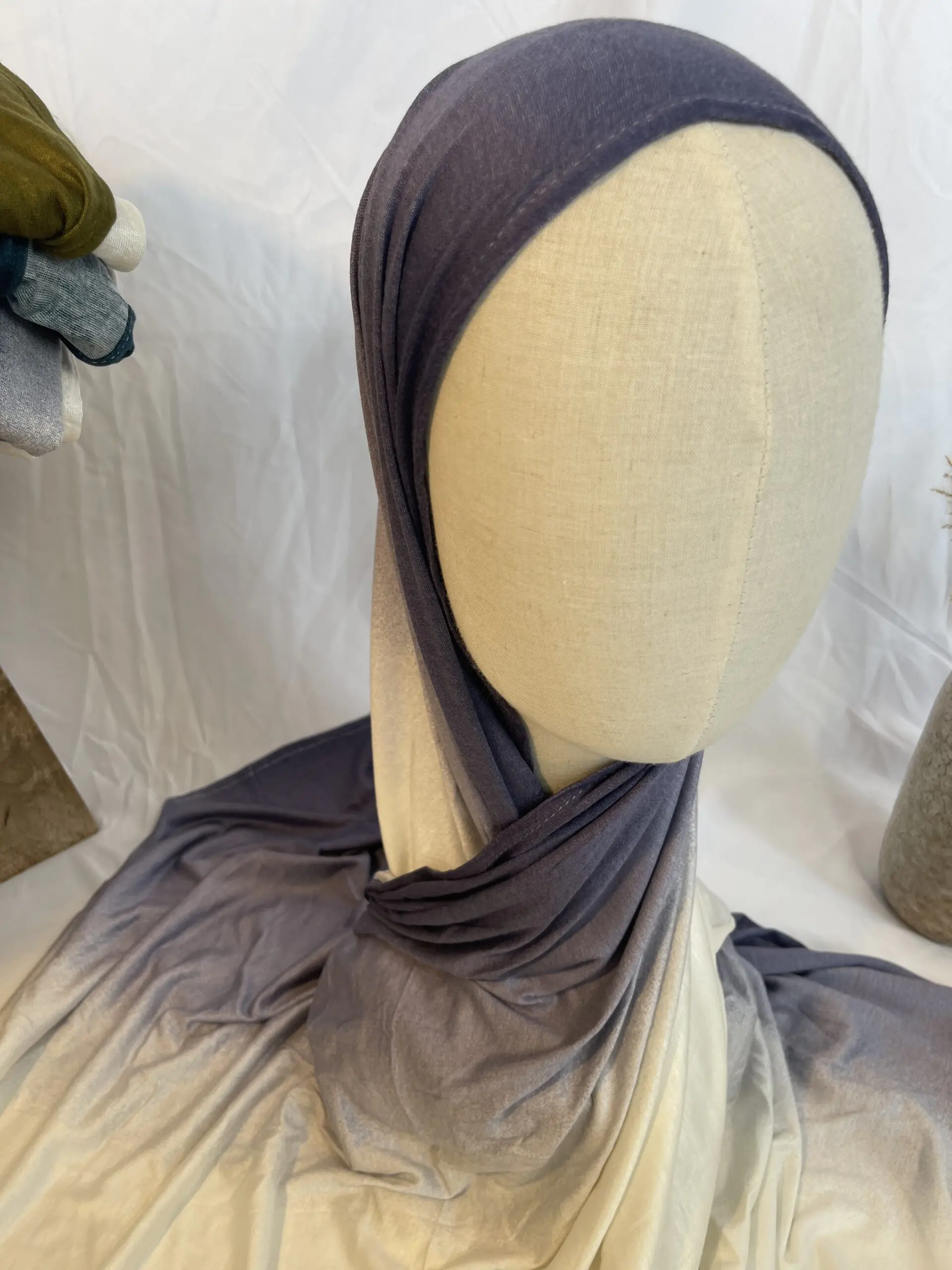 Hijab en jersey lycra avec un d&eacute;grad&eacute; de couleurs allant du gris ardoise fonc&eacute; au cr&egrave;me clair, pr&eacute;sent&eacute; sur un mannequin.