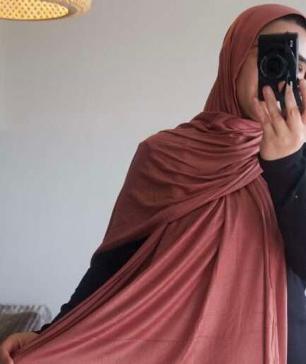 Hijab uni terracotta rosé en jersey Dubai premium (coton de haute qualité), montrant sa texture douce et son drapé, porté et roulé.
