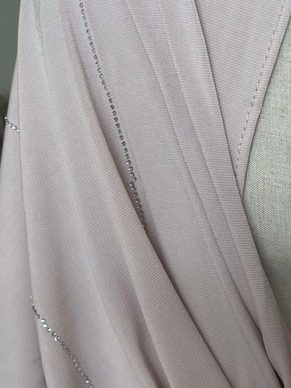 Hijab rose poudré clair en jersey doux avec de fines lignes de strass argentés scintillants, présenté sur un mannequin.