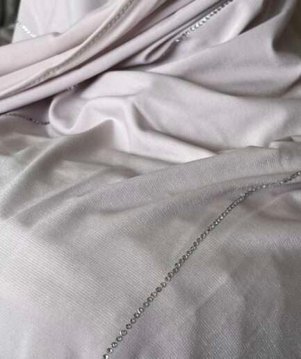 Hijab rose poudré clair en jersey doux avec de fines lignes de strass argentés scintillants, présenté sur un mannequin.