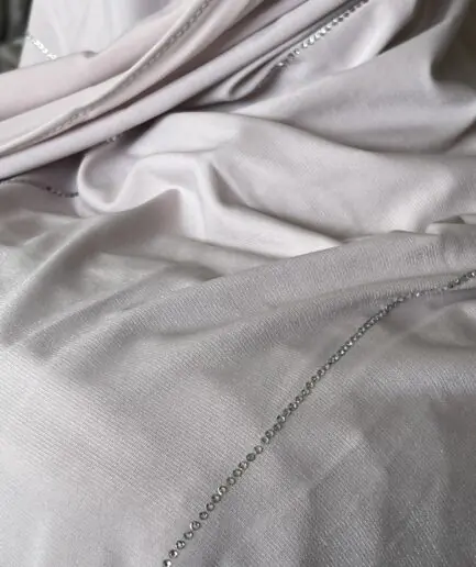 Hijab rose poudr&eacute; clair en jersey doux avec de fines lignes de strass argent&eacute;s scintillants, pr&eacute;sent&eacute; sur un mannequin.