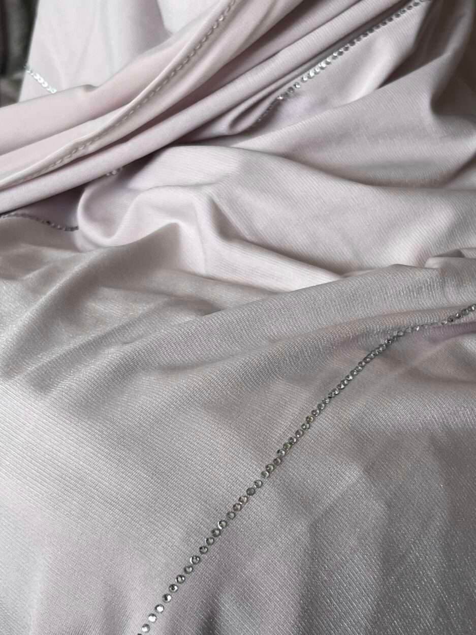 Hijab rose poudré clair en jersey doux avec de fines lignes de strass argentés scintillants, présenté sur un mannequin.