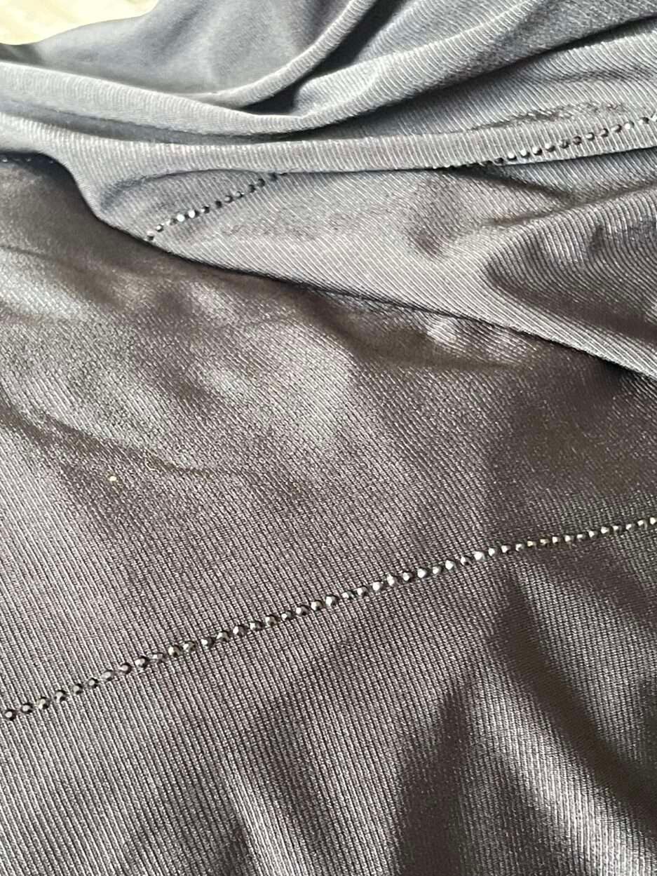 Hijab noir profond en jersey doux avec de fines lignes de strass foncés scintillants, présenté sur un mannequin.
