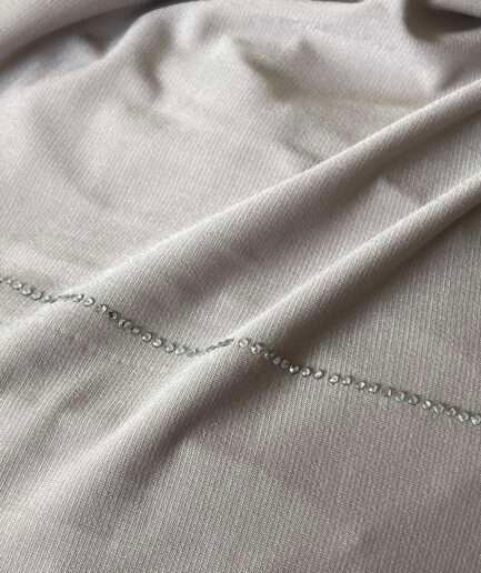 Hijab beige nude clair en jersey doux avec de fines lignes de strass argentés scintillants, présenté sur un mannequin.