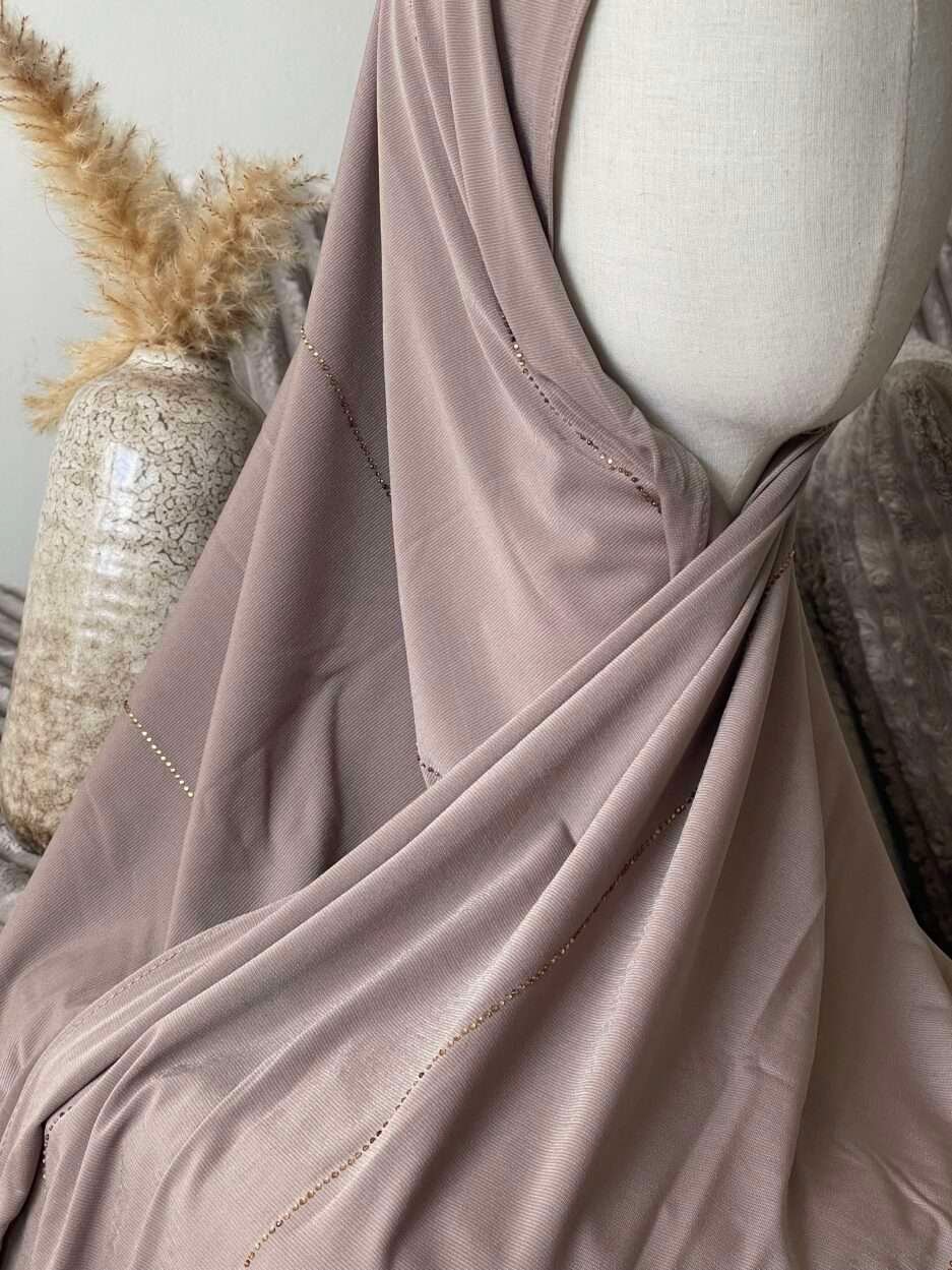 Hijab taupe rosé en jersey doux avec de fines lignes de strass dorés scintillants, présenté sur un mannequin.