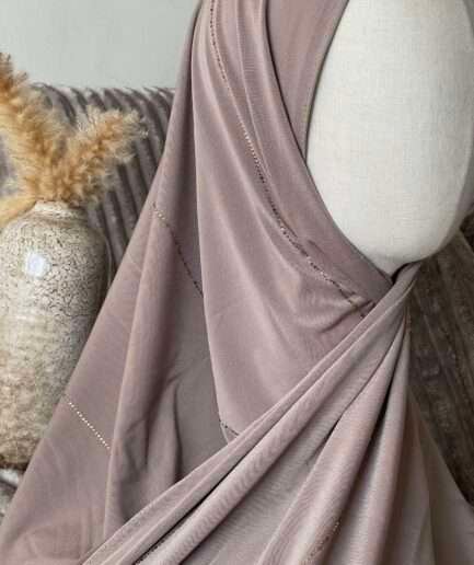 Hijab taupe rosé en jersey doux avec de fines lignes de strass dorés scintillants, présenté sur un mannequin.
