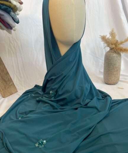 Hijab bleu canard uni en jersey doux, orné de broches de perles et strass assortis, présenté sur un mannequin.
