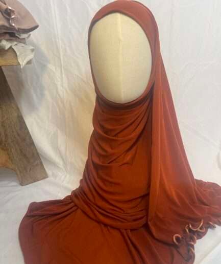 Hijab terracotta intense en jersey doux avec une fine bordure festonnée décorative, présenté sur un mannequin.