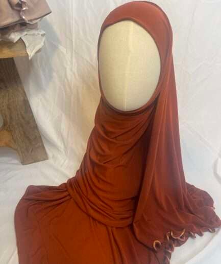 Hijab terracotta intense en jersey doux avec une fine bordure festonnée décorative, présenté sur un mannequin.