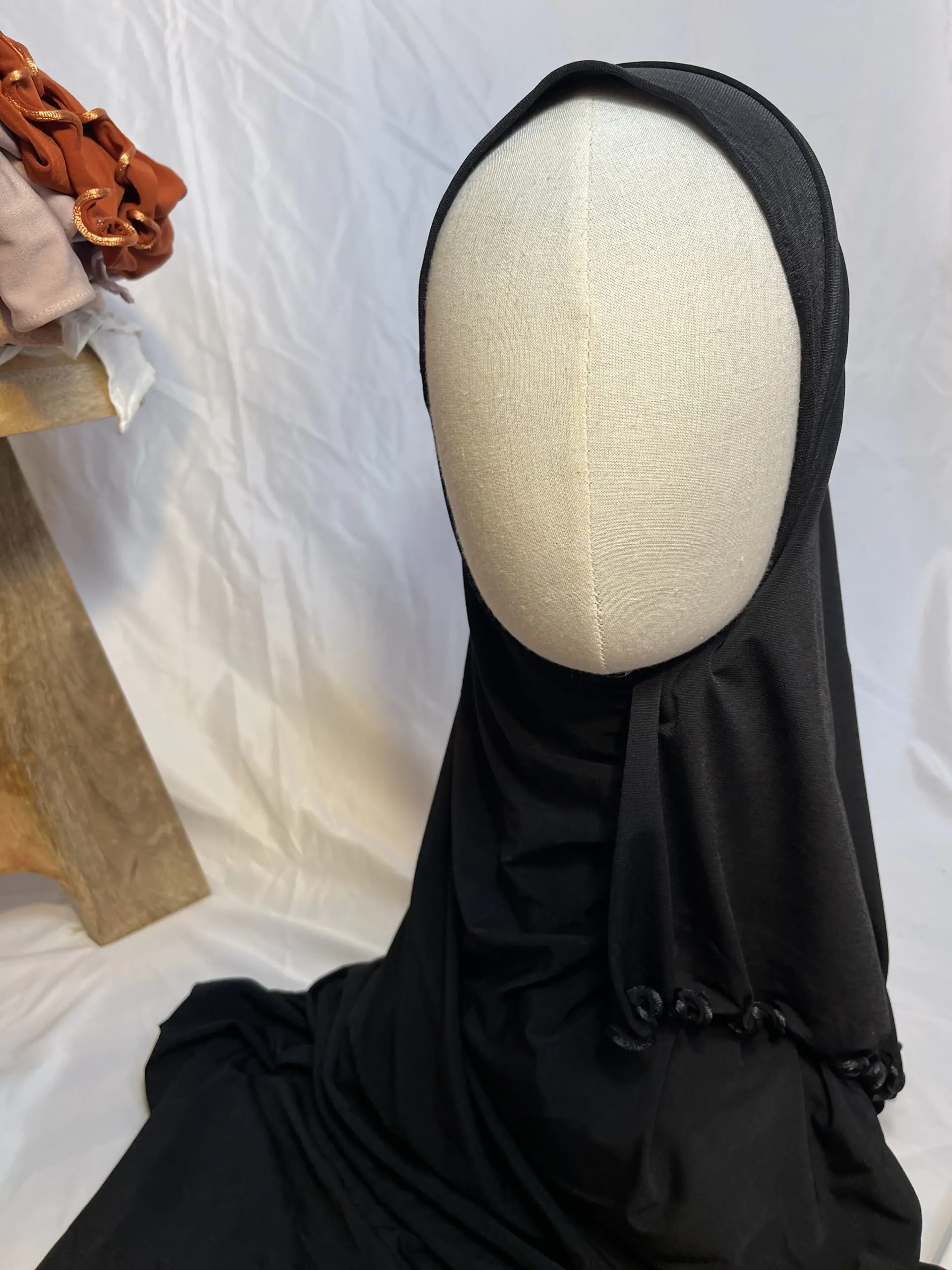 Hijab noir uni en jersey doux avec une fine bordure festonn&eacute;e d&eacute;corative, pr&eacute;sent&eacute; sur un mannequin.