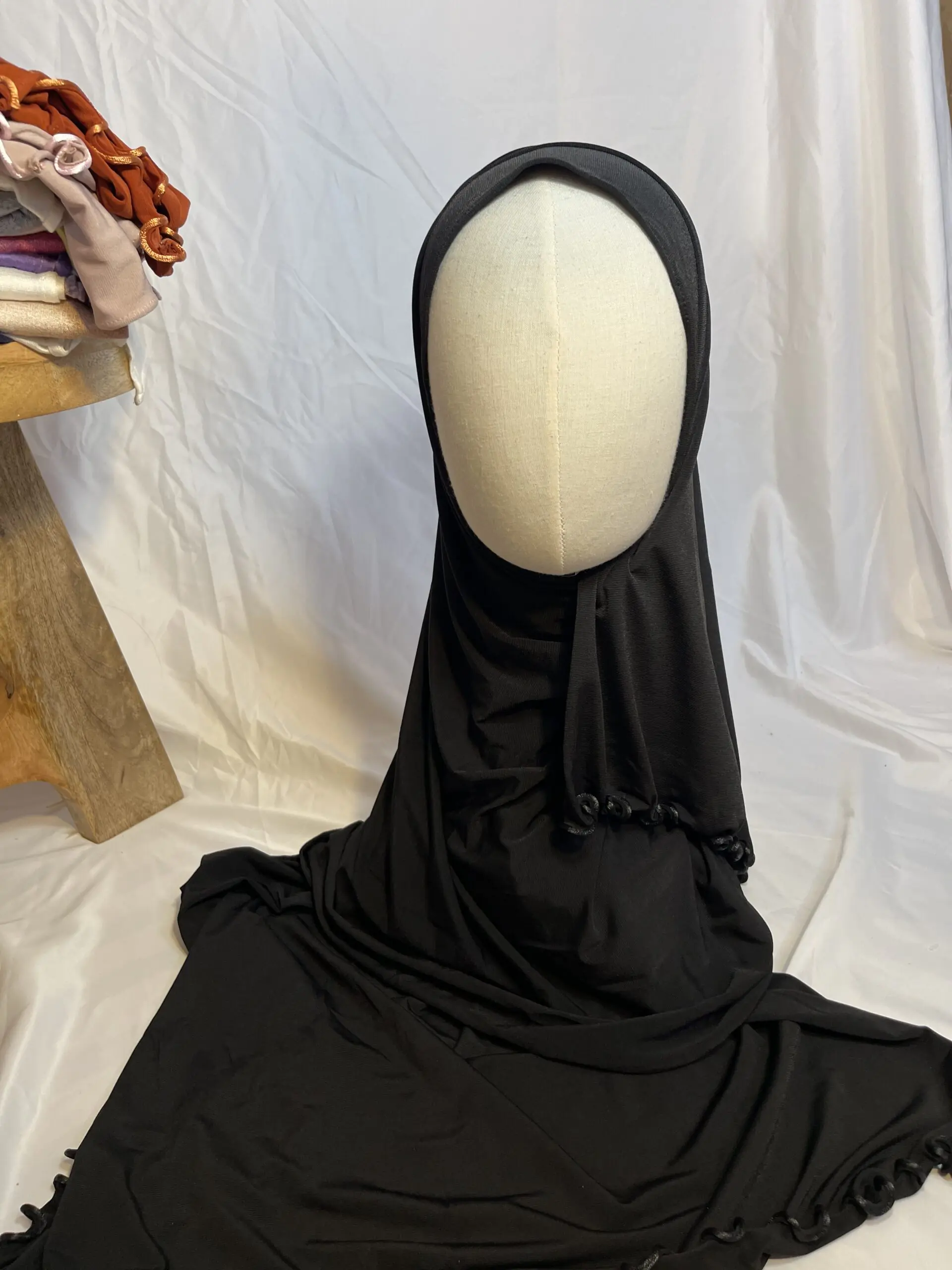 Hijab noir uni en jersey doux avec une fine bordure festonn&eacute;e d&eacute;corative, pr&eacute;sent&eacute; sur un mannequin.