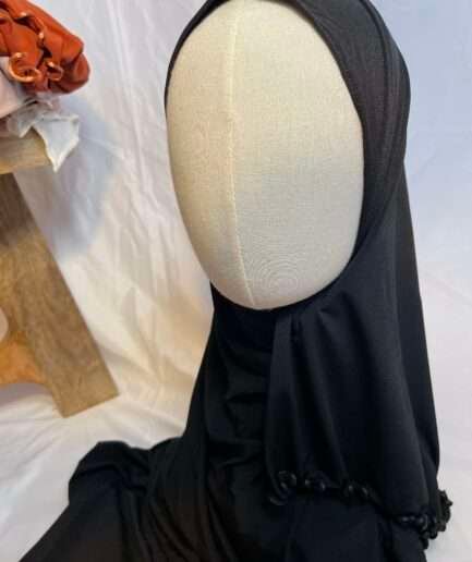 Hijab noir uni en jersey doux avec une fine bordure festonnée décorative, présenté sur un mannequin.