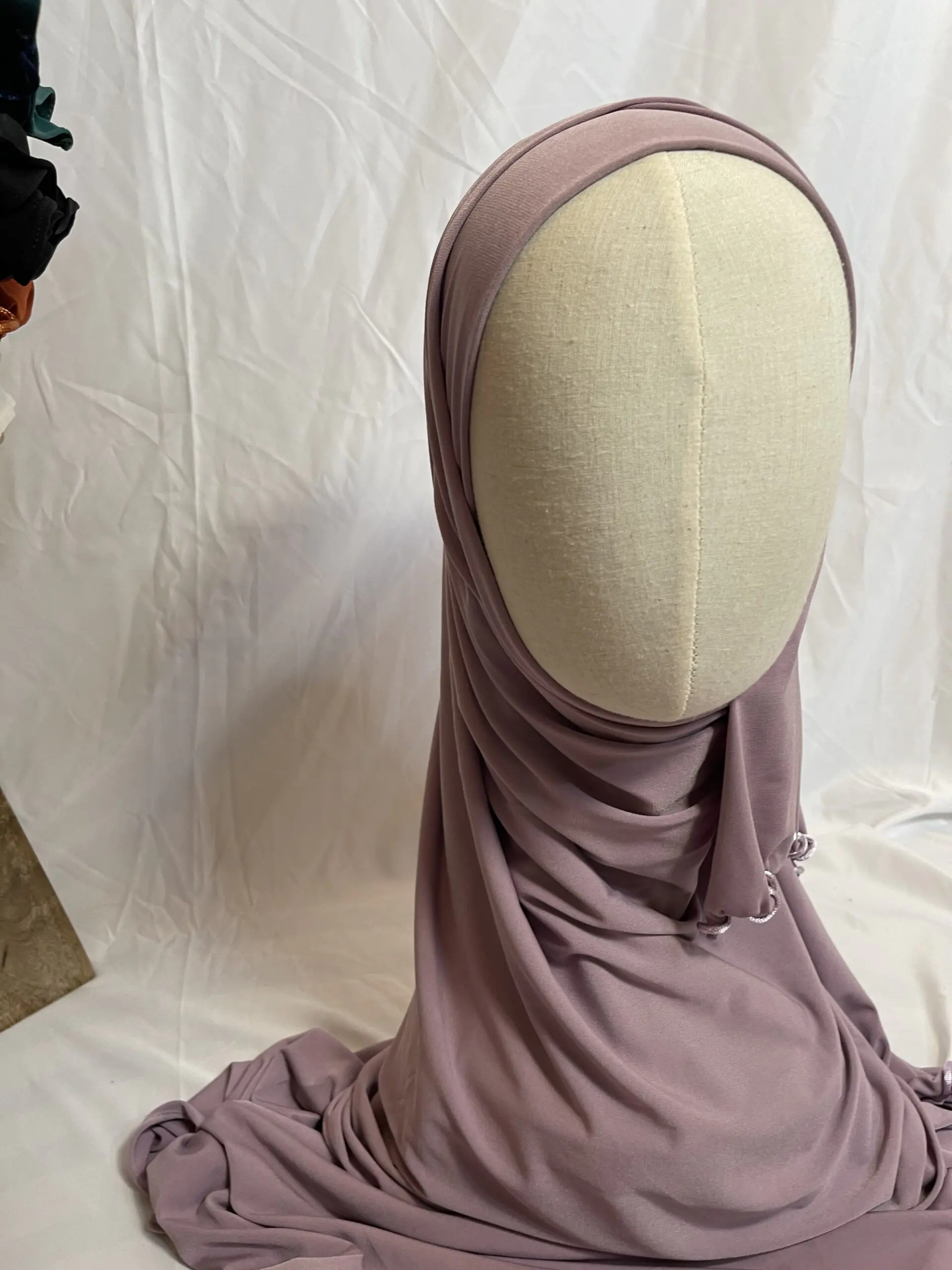 Hijab mauve poudr&eacute; uni en jersey doux avec une fine bordure festonn&eacute;e contrastante, pr&eacute;sent&eacute; sur un mannequin.