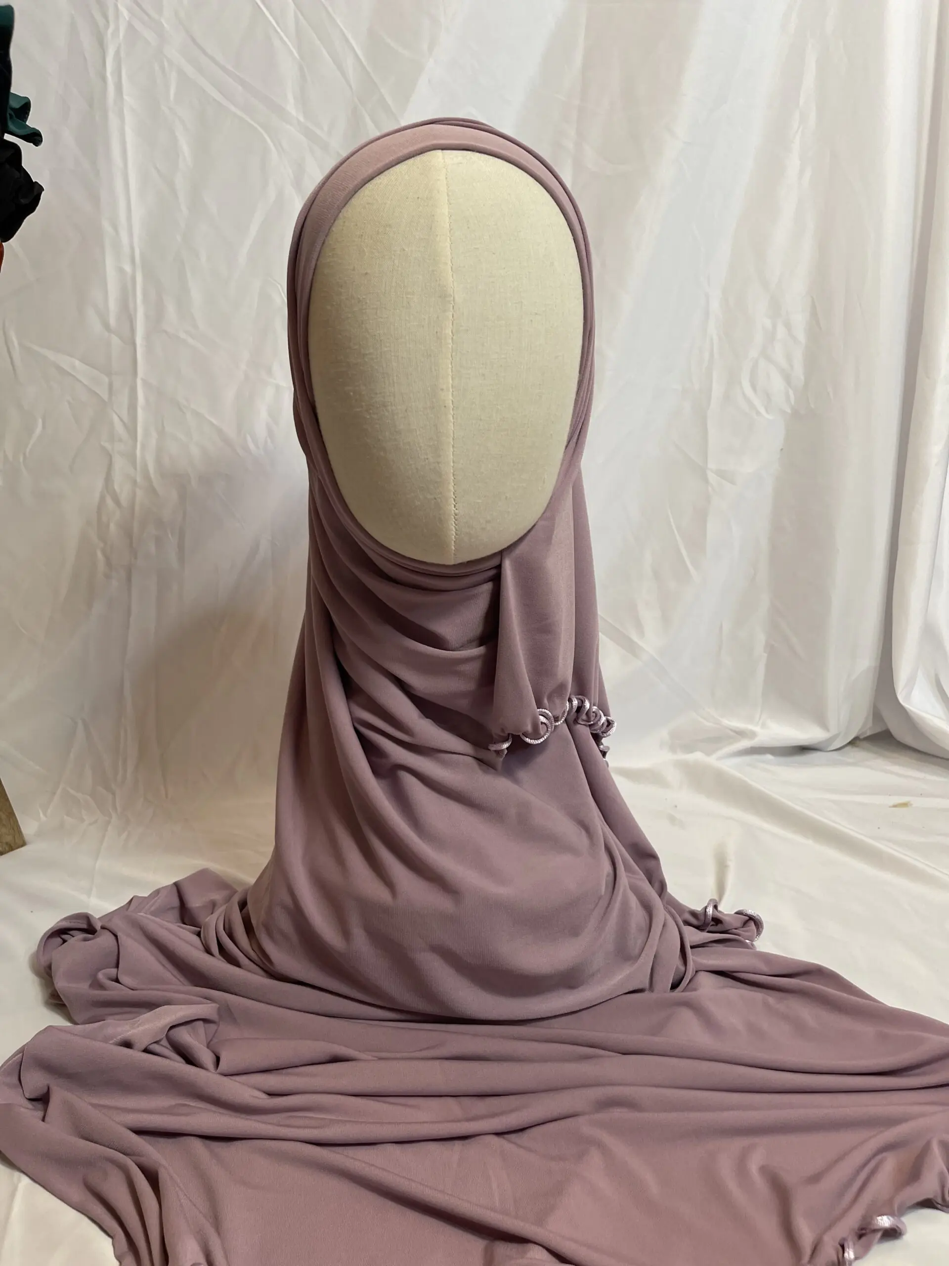 Hijab mauve poudr&eacute; uni en jersey doux avec une fine bordure festonn&eacute;e contrastante, pr&eacute;sent&eacute; sur un mannequin.