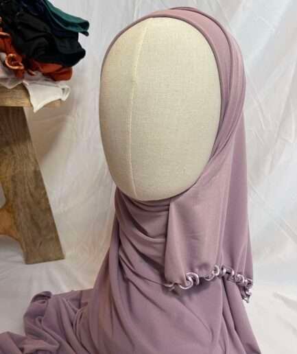 Hijab mauve poudré uni en jersey doux avec une fine bordure festonnée contrastante, présenté sur un mannequin.