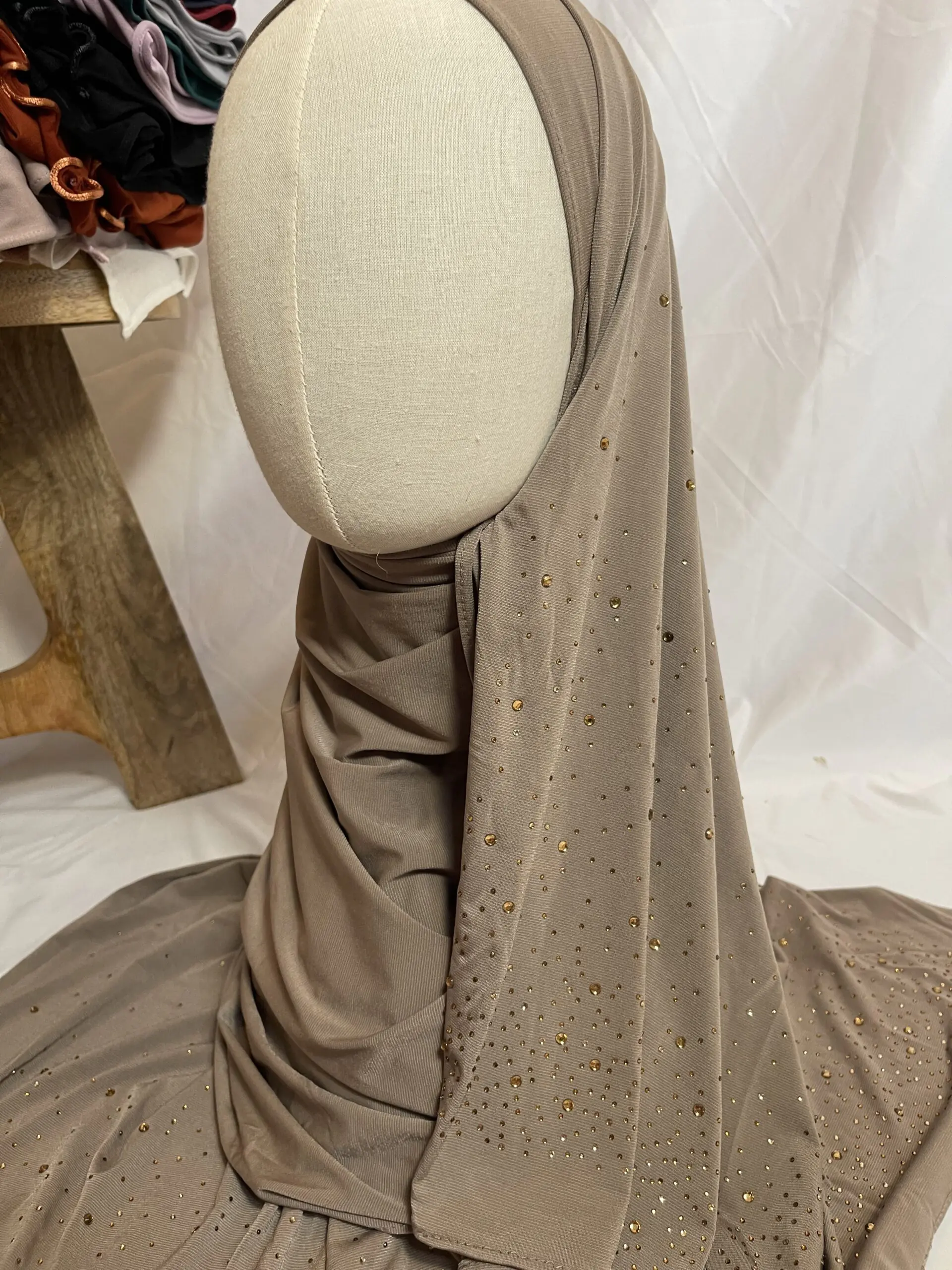 Hijab taupe en jersey doux, parsem&eacute; de petits strass dor&eacute;s scintillants effet ciel &eacute;toil&eacute;, pr&eacute;sent&eacute; sur un mannequin.