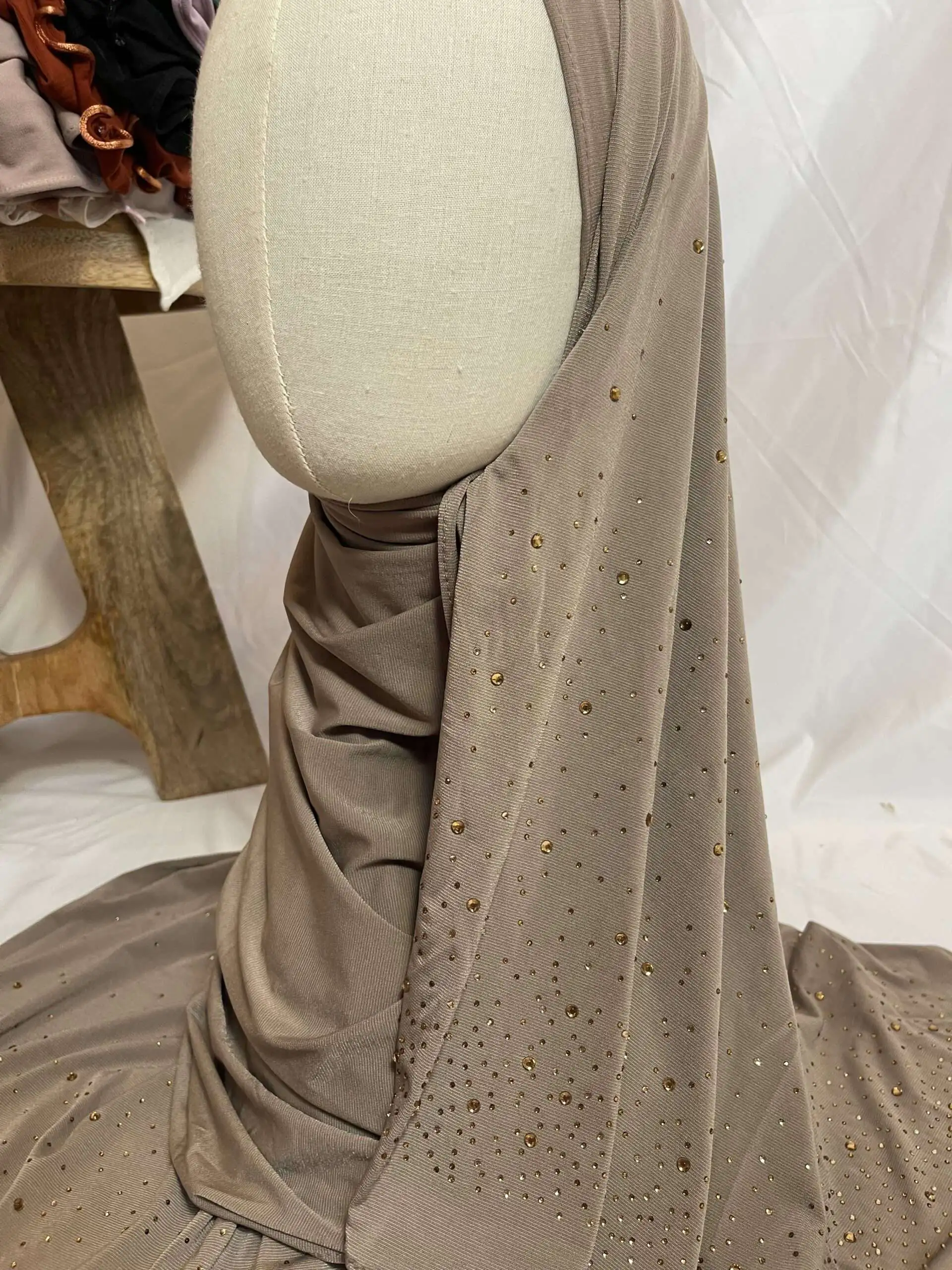 Hijab taupe en jersey doux, parsem&eacute; de petits strass dor&eacute;s scintillants effet ciel &eacute;toil&eacute;, pr&eacute;sent&eacute; sur un mannequin.
