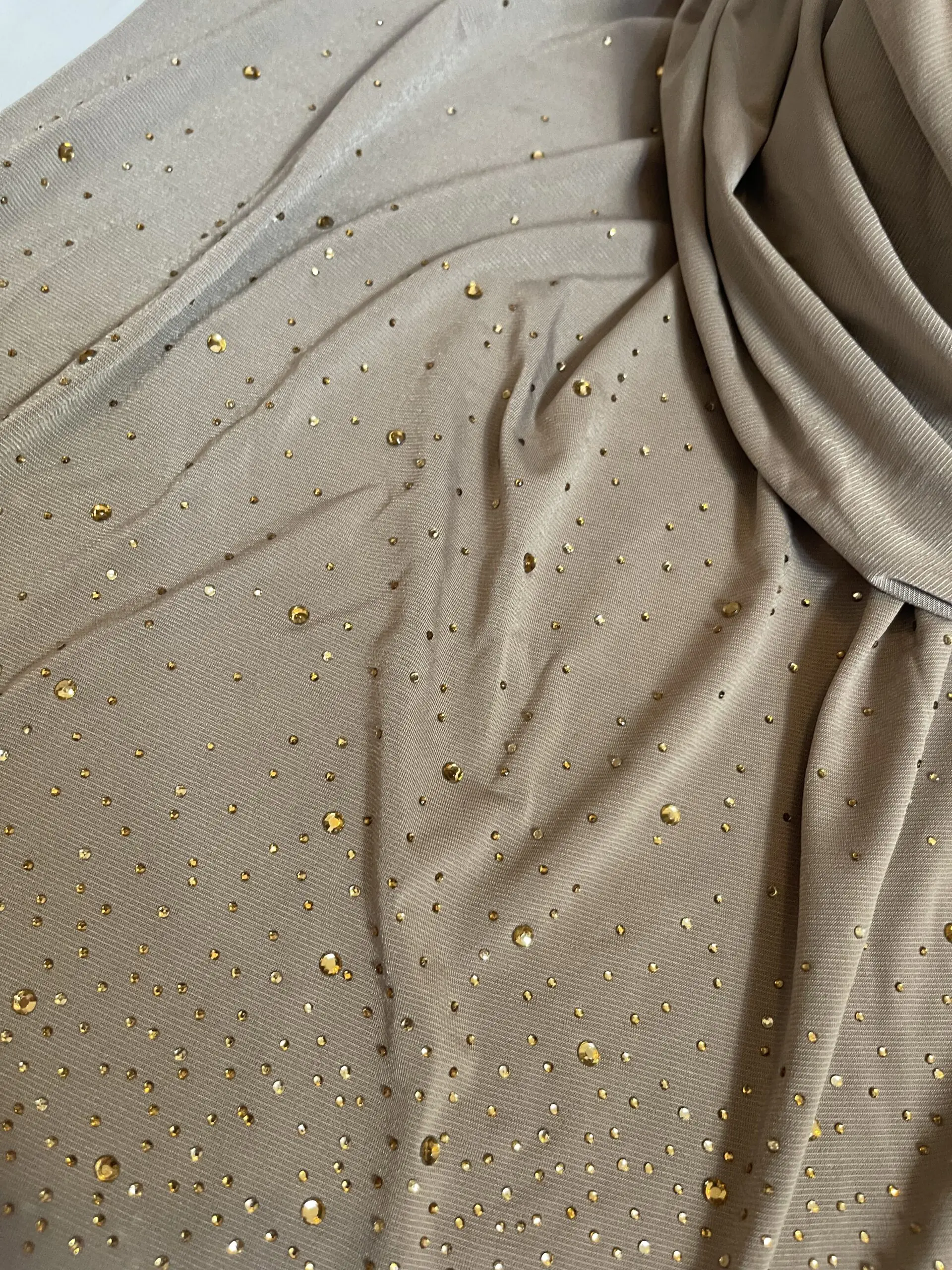 Hijab taupe en jersey doux, parsem&eacute; de petits strass dor&eacute;s scintillants effet ciel &eacute;toil&eacute;, pr&eacute;sent&eacute; sur un mannequin.